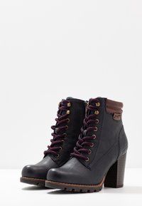 Botas de cuero negras hasta el tobillo con una superficie texturizada, cordones burdeos, ojales dorados, acentos de cuero marrón y un tacón apilado.