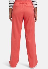 Coral wide-leg pants with an elastic waistband, featuring back pockets and a smooth, lightweight fabric texture.
