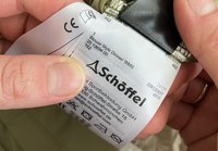 Label tag for a green blouse, featuring care instructions, size, and brand logo "Schöffel," with a white background and black text.