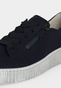 Baskets bleu foncé avec lacets noirs, une fermeture éclair latérale et une semelle épaisse blanche texturée.