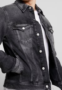 Jeansjacka i svart med en gradienteffekt, med silverdetaljer, knäppningar, bröstfickor och stygn detaljer.