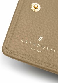 Taccuino in pelle beige testurizzata con accessori dorati. Presenta un logo impresso "LAZAROTTI" e "est. 2007" sulla copertina.