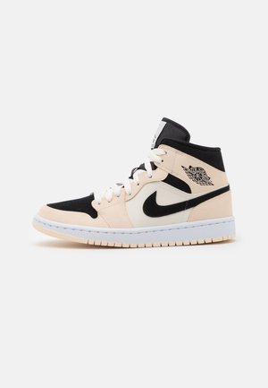 Baskets montantes Air Jordan en beige, noir et blanc avec le logo swoosh de Nike et le logo aile "Air Jordan" sur le côté, lacets blancs et semelle en caoutchouc.