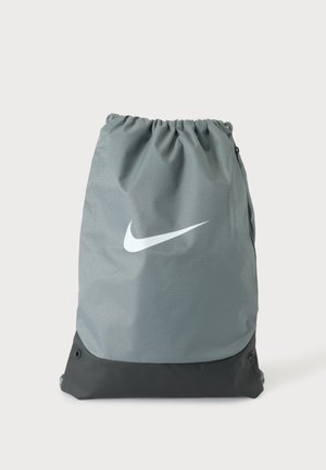 Γκρι και μαύρο σακίδιο πλάτης Nike με κορδόνι, με λευκό λογότυπο swoosh στο κέντρο μπροστά και εσωτερικό κλείσιμο στην κορυφή.