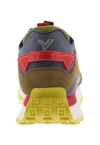 Scarpa sportiva con tacco in suede marrone, parte superiore blu, dettagli rossi e suola gialla con grip testurizzato. Logo del marchio sulla parte posteriore e laterale.