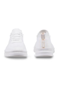 Weiße Sneakers mit Mesh-Design, runder Zehenpartie und Schnürsenkeln. Die Rückseite zeigt ein strukturiertes Panel mit einem kontrastierenden goldenen Akzent-Tag.