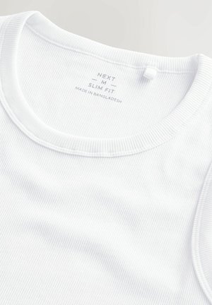 White ribbed tank top with a round neckline. Features a tag reading "NEXT M SLIM FIT" and "MADE IN BANGLADESH." Smooth texture, fitted design.