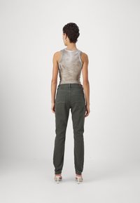 Top corto ajustado en un patrón gris mármol combinado con pantalones de tiro alto verdes olivo, que cuentan con bolsillos traseros y un corte recto.