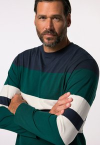 Chemise à manches longues avec des rayures horizontales bleu marine, vert et blanc, fabriquée dans un tissu doux, avec un col rond et une coupe décontractée.