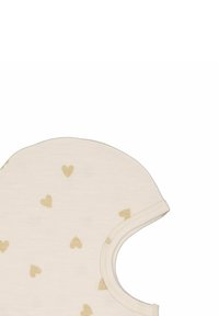 Ljusbeige tyg med små guldhjärtmönster. Rund form med vid halsöppning och subtilt texturerad yta.