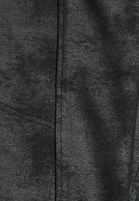 Black textured fabric featuring a subtle pattern, with stitching details and a sleek, smooth surface throughout.