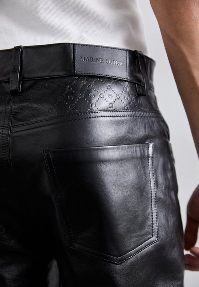 Μαύρο δερμάτινο παντελόνι με υφασμάτινη μέση με ανάγλυφο σχέδιο, πίσω τσέπη με λεπτομέρεια ραφής και ετικέτα Marine Serre.