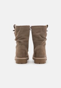 Botines de ante marrón con un diseño arrugado, que presentan una puntera redonda y una suela resistente. Las pestañas en la parte posterior añaden un detalle funcional.