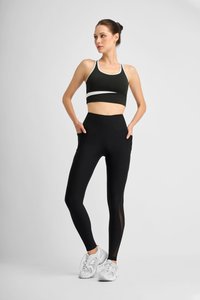 Black high-waisted leggings with side pockets and mesh panels, paired with a sleeveless dark green sports bra with white accents.