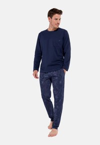 Marineblaues Langarmshirt mit einer Brusttasche, kombiniert mit gemusterten dunkelblauen Jogginghosen mit Blattdesigns. Weicher, bequemer Stoff.