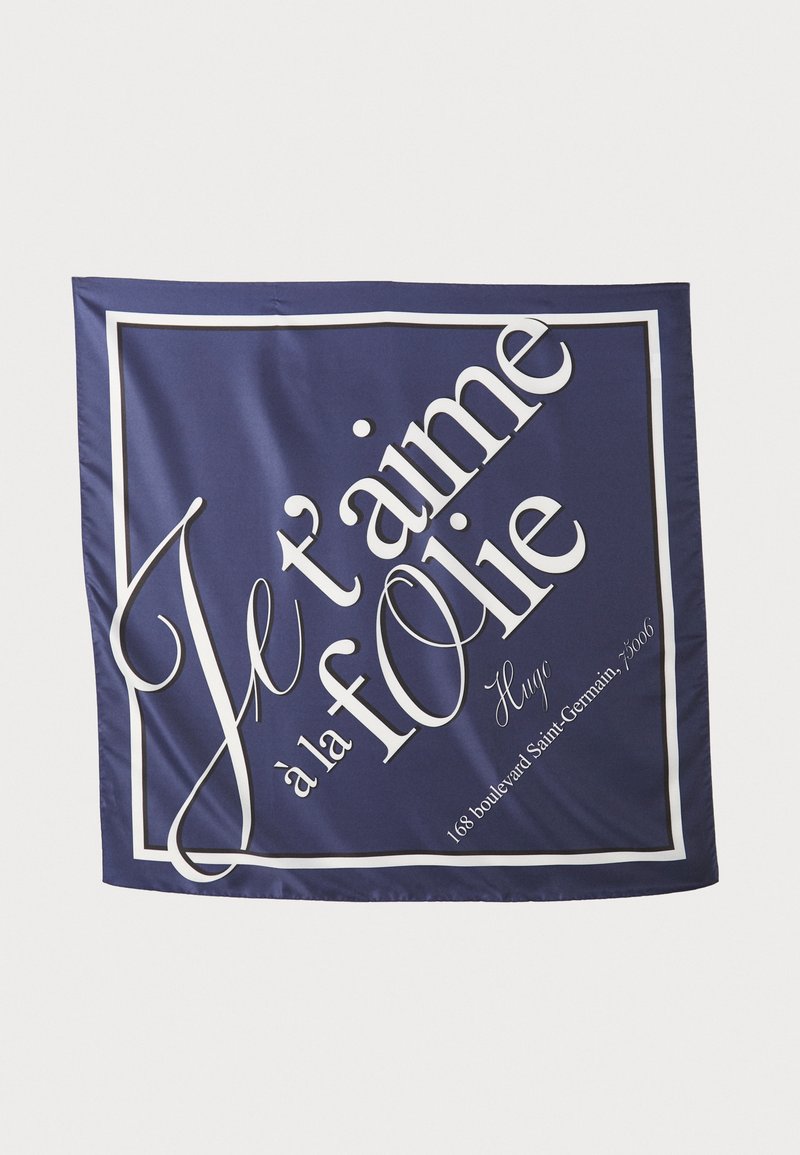 Navy silk scarf featuring white text that reads "Je t'aime à la folie" and "Hugo" with a rectangular border. Text in varied font styles.