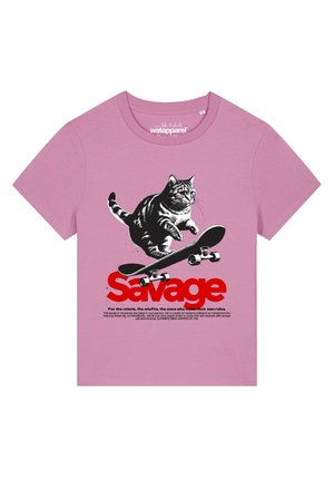 T-shirt rose avec un chat noir et blanc sautant sur un skateboard au-dessus du texte rouge vif "Savage" en caractères gras, avec un texte inspirant plus petit en dessous.