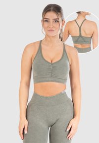 Elastisk sport-bh i olivgrön, med en rynkad front, tunna axelremmar och en kortad design. Tyget har en slät, mjuk struktur.