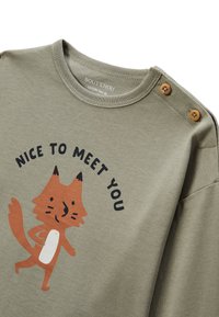 T-shirt en coton vert avec un dessin de renard cartoon, accompagné du texte "RAVI DE TE RENCONTRER" au-dessus. Doté de boutons en bois sur l'épaule.