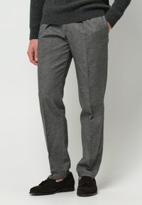 Grau zugeschnittene Hosen mit feiner Textur und scharfen Falten, ausgestattet mit einem flachen Frontdesign, getragen mit dunklen Wildleder-Pantoletten.