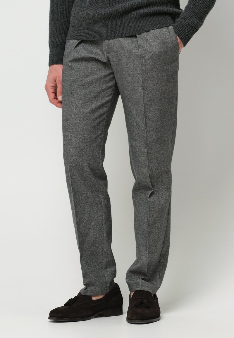 Grau zugeschnittene Hosen mit feiner Textur und scharfen Falten, ausgestattet mit einem flachen Frontdesign, getragen mit dunklen Wildleder-Pantoletten.