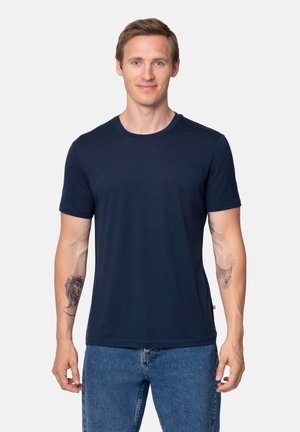 Camiseta de algodón de color azul marino con cuello redondo, mangas cortas y un corte holgado, que presenta una pequeña etiqueta con logo en el lado inferior.