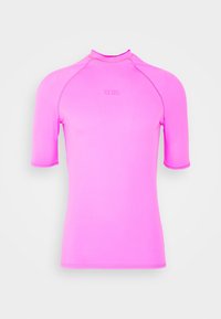 T-shirt de sport à manches courtes rose vif avec col montant et logo discret "GCDS" sur la poitrine, présenté sur fond blanc uni.