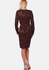 Braun eng anliegendes Kleid mit langen Ärmeln, das ein dezentes Blumenmuster, strukturierten Stoff und einen knielangen Saum aufweist. Wird hinten geschlossen.