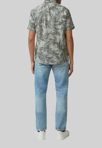 Korte mouw shirt met een grijs palmbladpatroon, gecombineerd met lichtblauwe jeans en witte sneakers. Het shirt heeft een casual kraagontwerp.