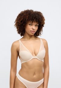 Bež modrček s žico in prosojnimi mrežastimi paneli, globokim V-izrezom, nastavljivimi naramnicami in usklajenimi bikinami z logirano elastično pasom.