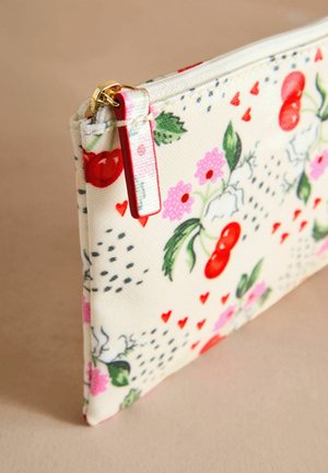 Floral print zip pouch with a textured cream fabric, featuring red cherries and pink flowers, with gold zipper and red accent tag.