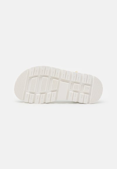 Suola di sneaker bianca in gomma testurizzata, con scanalature e creste profonde per una migliore aderenza. Design semplice con area di allacciatura standard nella parte superiore.