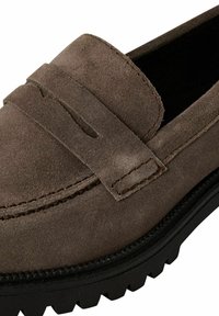 Braune Wildlederloafer mit runder Zehenform, genähten Details und einem auffälligen Penny Keeper-Band. Die Sohle besteht aus strukturiertem Gummi für besseren Halt.