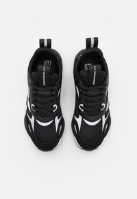 Svarta mesh-sneakers med vita accenter, med rund tå, plana snören och dragflik. Mångsidiga material ger flexibilitet och stöd.