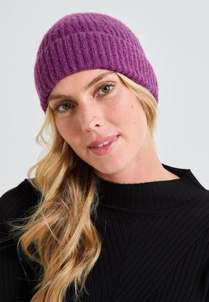 Gorro de punto acanalado morado con una textura suave, llevado con un suéter negro de punto acanalado. Presenta un ajuste ceñido y un brillo sutil.