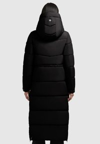�Čierna vyp padded parka s kapucňou, so zv horizontalným prešívaním a detailom tlačidla. Dlhá dĺžka a bočný zips na manžetách. Hladká textúra.