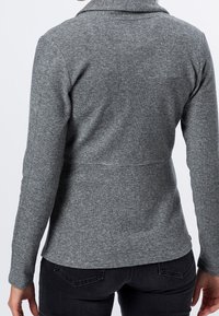 Pull gris côtelé avec col, manches longues et taille cintrée. Vue de dos montrant une texture lisse et un ourlet légèrement incurvé.