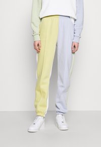 Un pantalon de survêtement avec un design en coloris pastel jaune, vert et bleu. Fabriqué en tissu doux avec des poignets et une taille élastiques.
