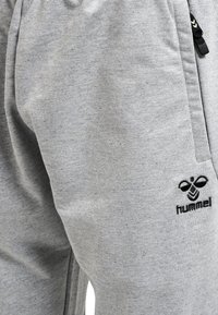 Graue Jogginghosen aus Baumwollmischung mit einem weichen Stoff, elastischem Bund und schwarz gesticktem Logo auf der linken Seite.