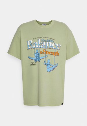 Lichtgroen katoenen t-shirt met een grafisch ontwerp van turners en de tekst "Flexibiliteit, Balans & Kracht" in blauw en oranje.