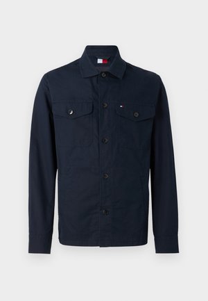 Dunkelblaue Jacke aus Baumwolle. Verfügt über eine Knopfleiste, zwei Brusttaschen und einen Stehkragen. Glatte Textur mit minimalen Akzenten.