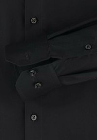 Schwarzes Hemd aus einem glatten Stoff mit spitzem Kragen, Doppelmanschetten und dunklen Knöpfen. Es sind keine Muster oder Akzente sichtbar.