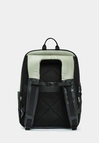 Zaino nero e grigio con schienale imbottito, spallacci regolabili, maniglia superiore e apertura rettangolare. Presenta una texture trapuntata e fibbie.