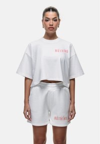 Set di t-shirt cropped bianca e pantaloni corti, in materiale cotone, con logo rosa "NOTHING", vestibilità ampia, scollo rotondo e cintura elastica.