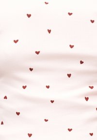 Witte stof met een patroon van kleine, verspreide rode hartjes die gelijkmatig over het oppervlak zijn verdeeld.