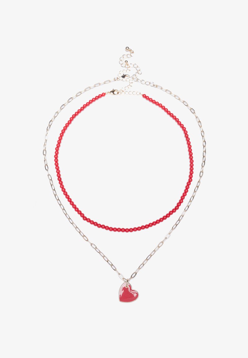 Collana di perline rosse sovrapposta a una catena di link in argento, con un pendente a forma di cuore rosso lucido. Complessivamente leggera e dal design semplice.