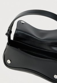 Borsa a mano in pelle nera con chiusura a patta magnetica e tasca interna con zip, mostrata aperta con una tracolla curva.