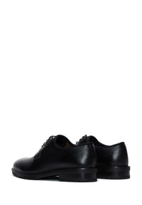 Zapatos de cuero negro con un acabado texturizado, punta redondeada, tacón bajo y diseño clásico de cordones; cuentan con costuras mínimas y acentos lisos.