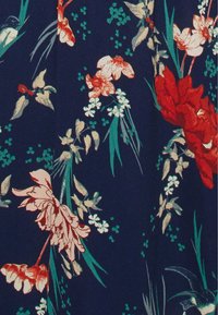 Tessuto con stampa floreale caratterizzato da grandi fiori rossi e bianchi su uno sfondo blu scuro, con foglie verdi e piccoli accenti floreali.