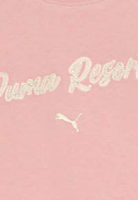 Svetloružový bavlnený tričko s nápisom "Puma Resort" v smotanovej výšivke a malým smotanovým logom Puma blízko lemu. Hladká textúra.